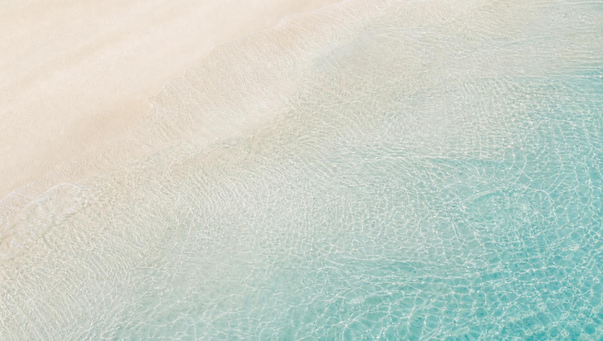 Soft sand and shallow turquoise water in a clean, minimal coastal texture