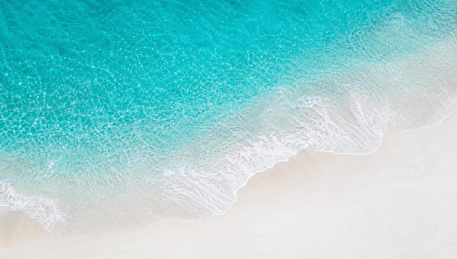 Aerial view of turquoise water meeting sugar-white Emerald Coast sand